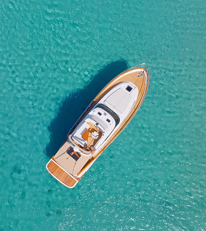 aerial of a luxury boat idling on crystal clear water